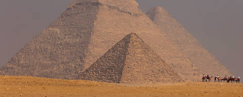 Tourists ride camels in front of the Great Pyramids of Giza, on the outskirts of Cairo, Egypt, October 26, 2022. REUTERS/Mohamed Abd El Ghany ORG XMIT: GGG-GHA04